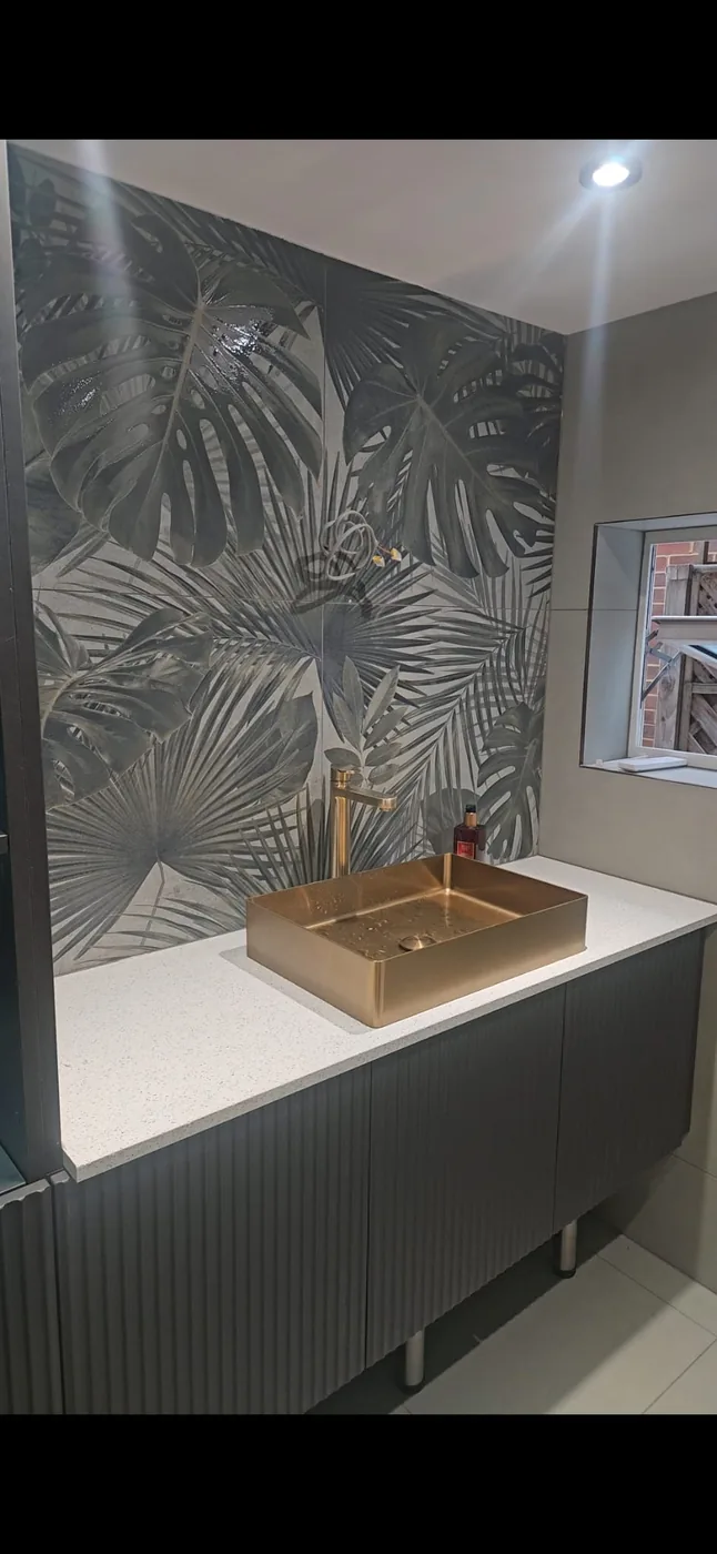 Brushed brass countertop basin · botanical tile splashback · fluted vanity