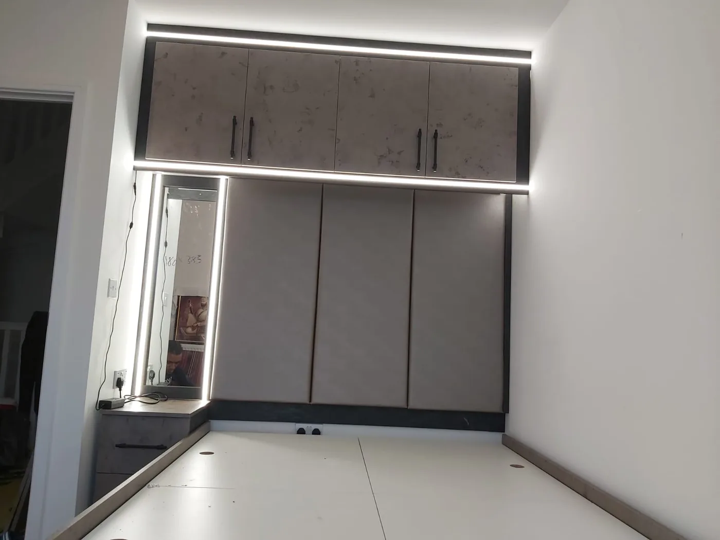 Stone-grey overbed wardrobes · LED strip · sliding doors