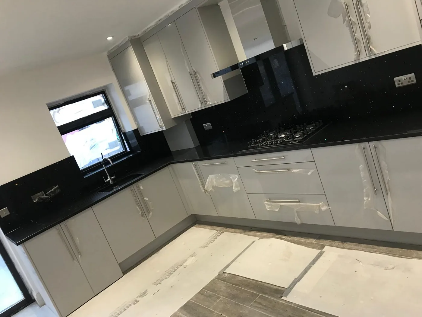 Pearl grey gloss kitchen · black sparkle worktop · curved glass extractor