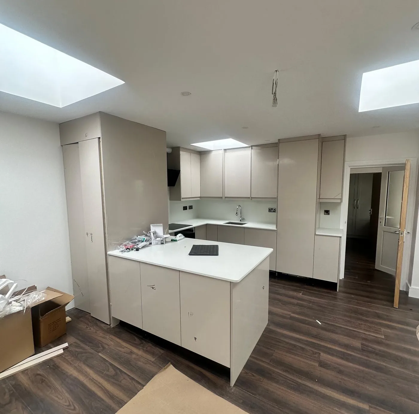 Taupe gloss L-shape kitchen · island · skylights