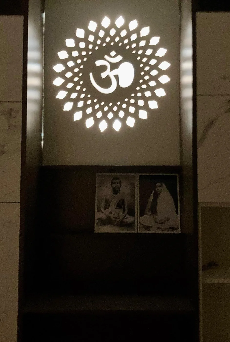 Backlit gold Om medallion · framed saint portraits