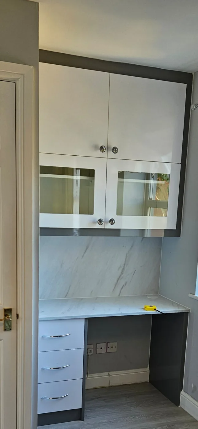White gloss desk unit · marble backsplash · glass-front cabinet