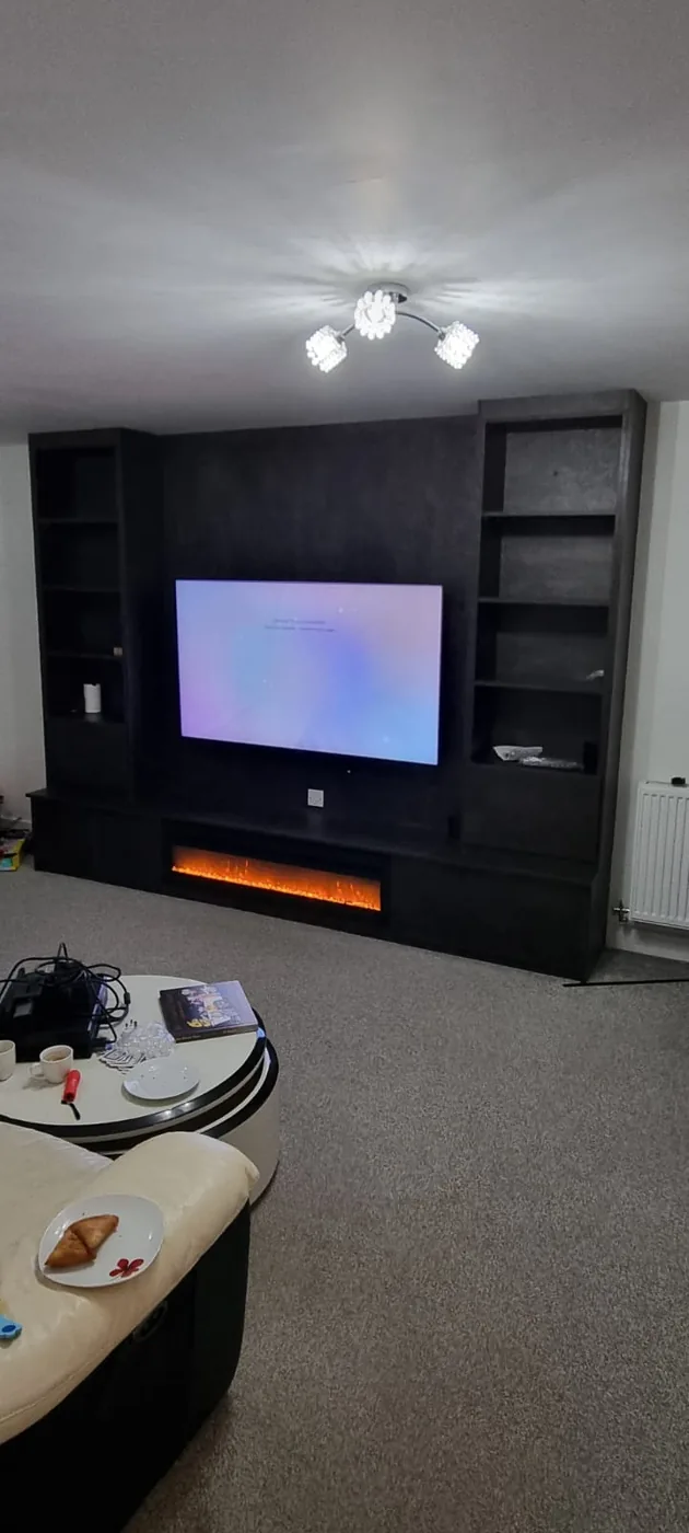 Charcoal full-wall media unit · open shelving · built-in fire