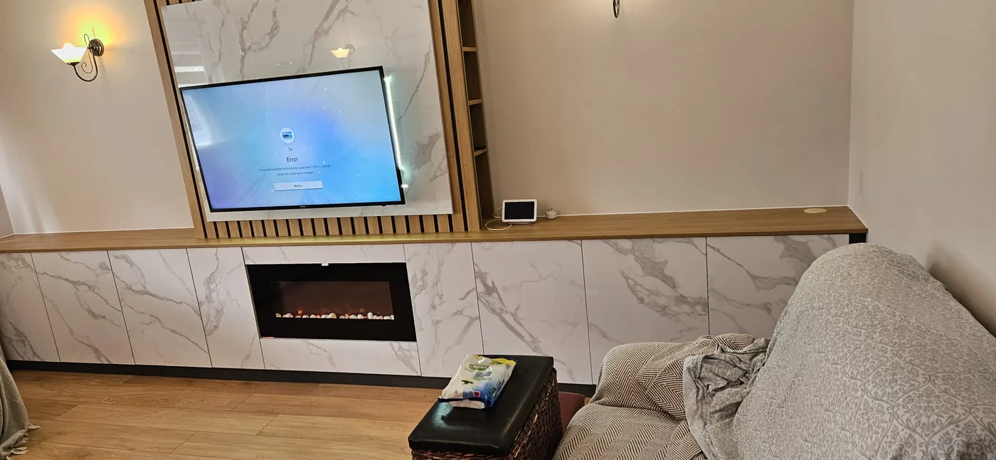 White marble-effect media wall · oak slat surround · built-in fire