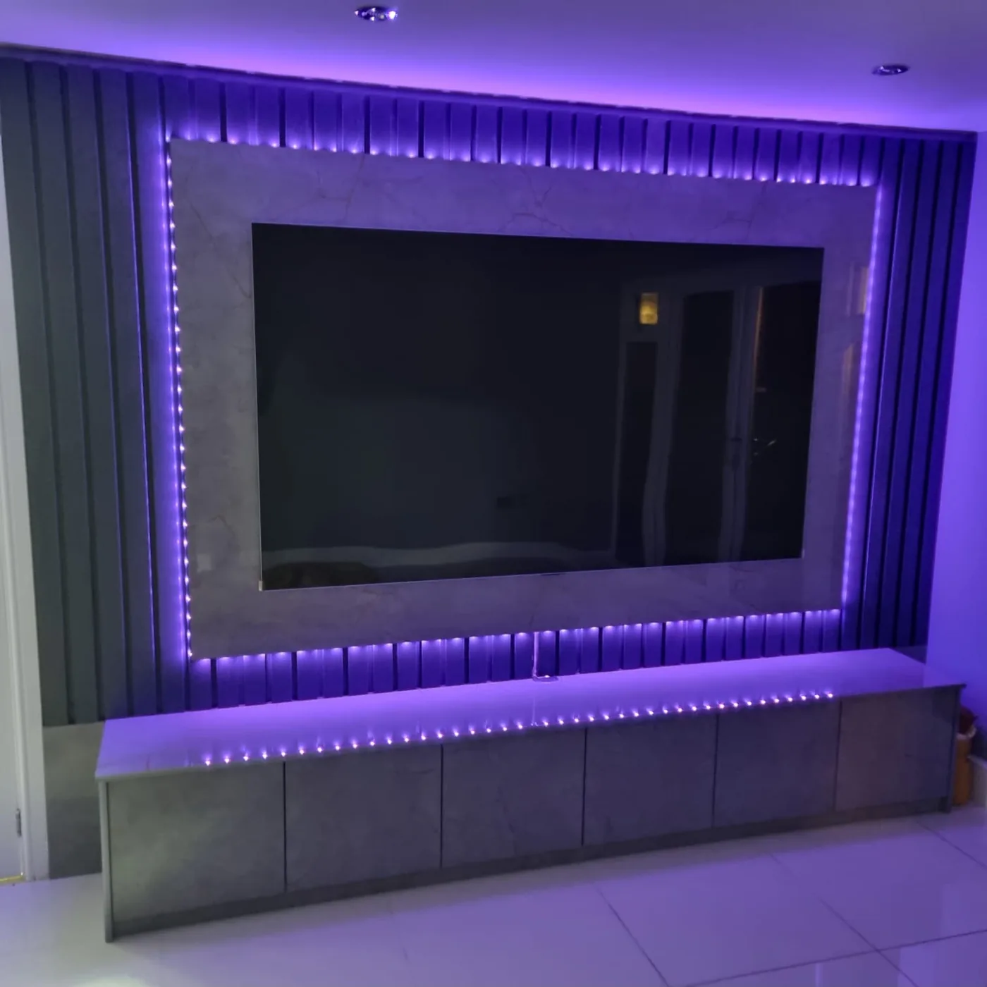Fluted grey stone media wall · RGB LED trim