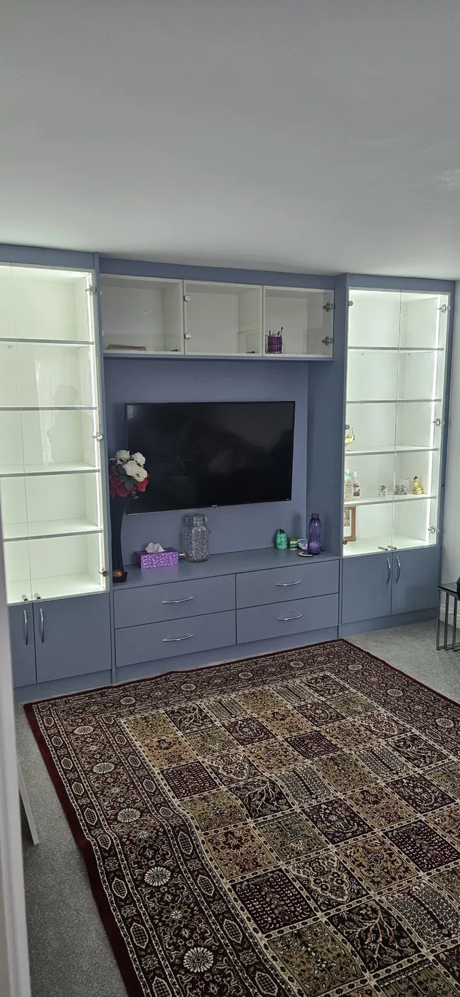 Powder blue full-wall media unit · glass display shelving