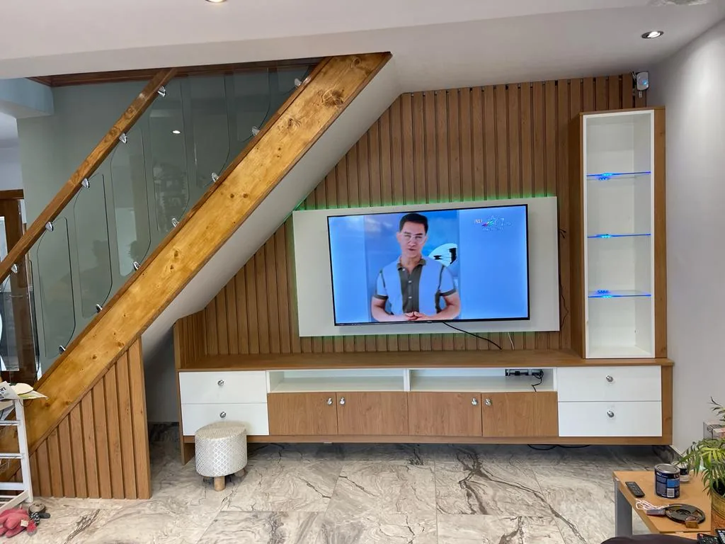 Under-stair media wall · oak slat TV surround · glass display shelf