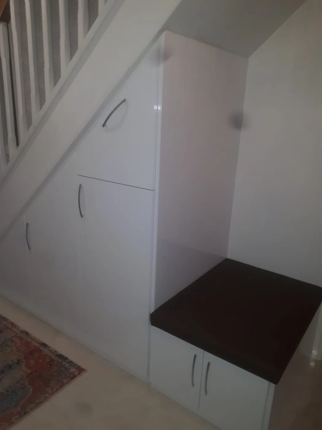 White gloss under-stair cupboards · built-in bench seat