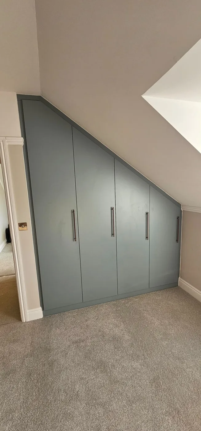 Slate-blue triangular loft wardrobe · hinged doors