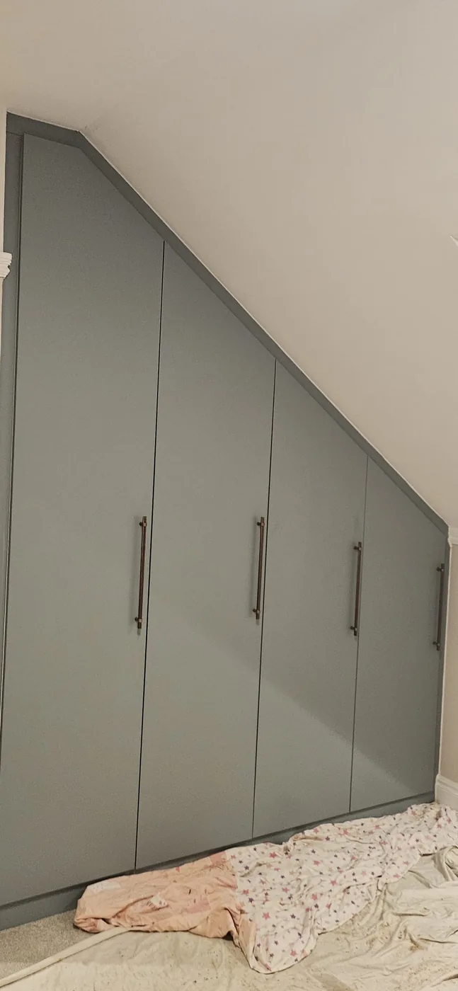 Slate-grey triangular loft wardrobe · brass handles
