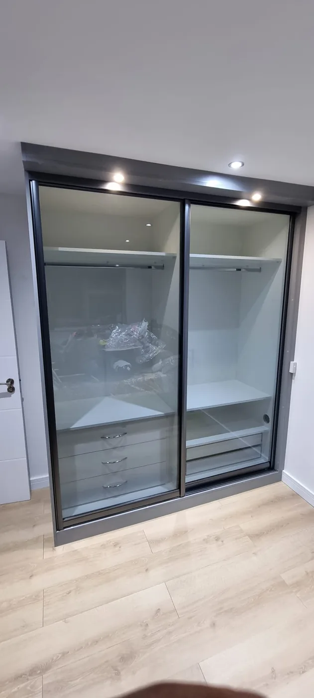 Black-framed glass sliding wardrobe · fitted drawers