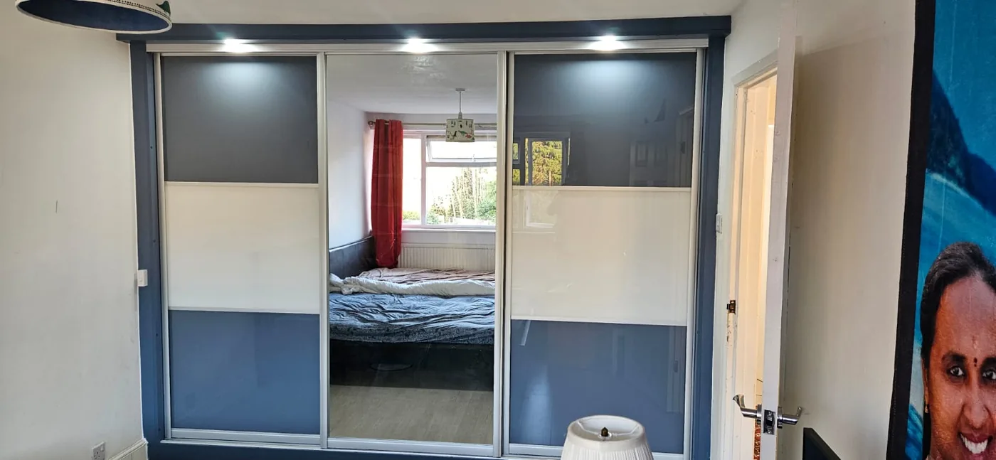 Blue-grey glass sliding wardrobe · mirror centre panel