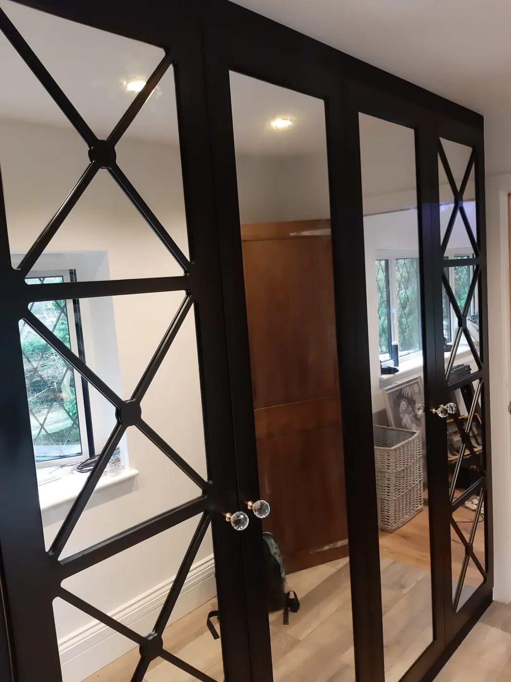 Black X-frame mirrored wardrobe · glass knob handles